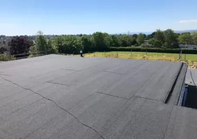 Flat roof with tar paper under sunny sky.