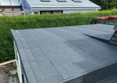 Flat roofing with shingles in residential backyard.