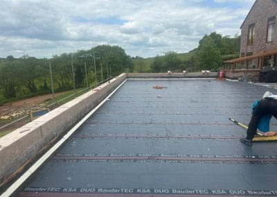 Flat roof waterproofing installation with scenic view.